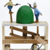 Carved wooden automata. 2 men in traditional cowboy outfits aim guns at each other either side of a grassy knoll. They alternate moving up and down.