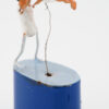 A miniature man in a white leotard lifts a woman in a ballet dress up in the air. They both have black hair and peach skin. They are mounted on a blue base with wire handle
