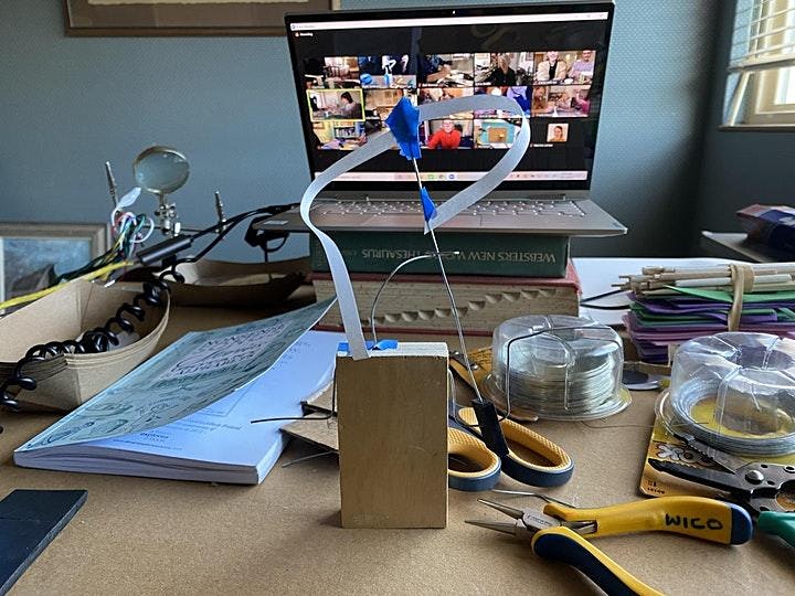 Tools and book and partial automata in front of a laptop with a conference call on screen.