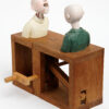 Carved painted wooden automata. 2 bald men are in conversation. One speaks and the other nods.