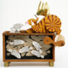 Wooden automata. A ginger cat with wings and halo sits atop a large fish tank.