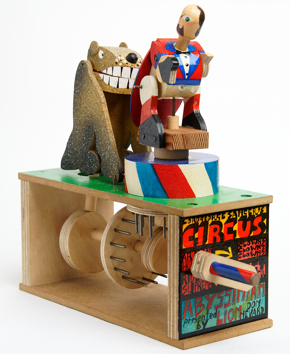 Brightly painted wooden automata. the ring master faces away from the lion.
