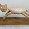 A carved wooden cat mid leap, held up by its springy articulated tail