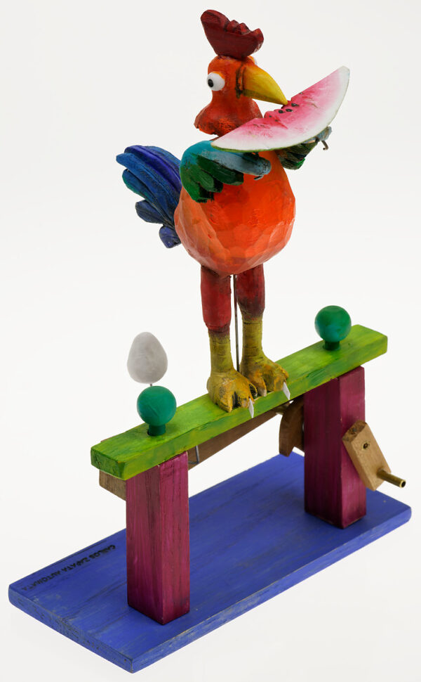 A brightly painted wooden automaton. The Rooster stands to devour a slice of watermelon