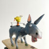 Hand carved and painted donkey with a yellow bird on his back.He stands on a wooden platform on an open frame contains cams, pulleys and levers.