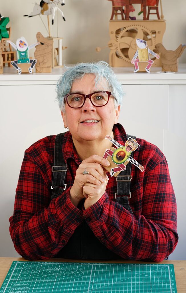 Portrait of Artist Loulou Cousin holding her mini collage automata