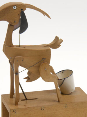 A wooden goat with one leg in a white metal bucket