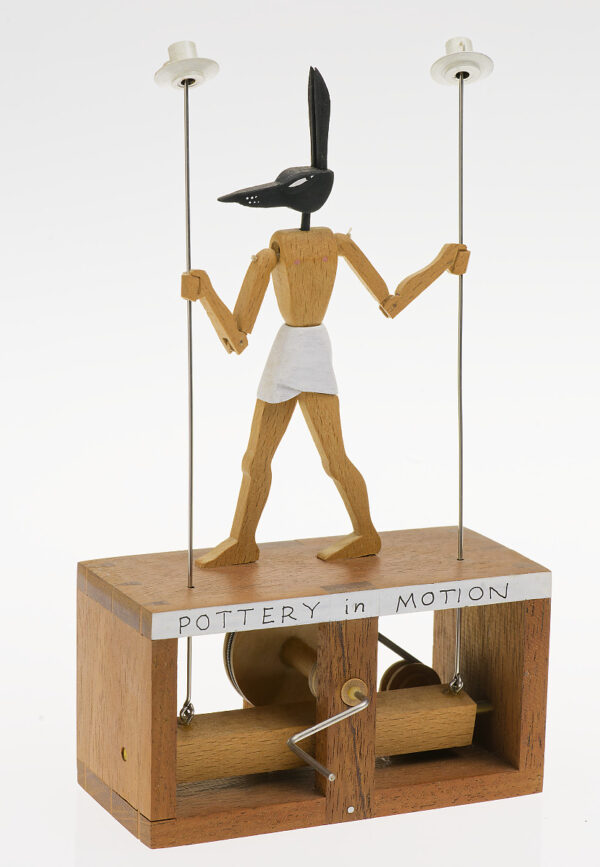 Anubis holds two thin poles with spinning cups on top.