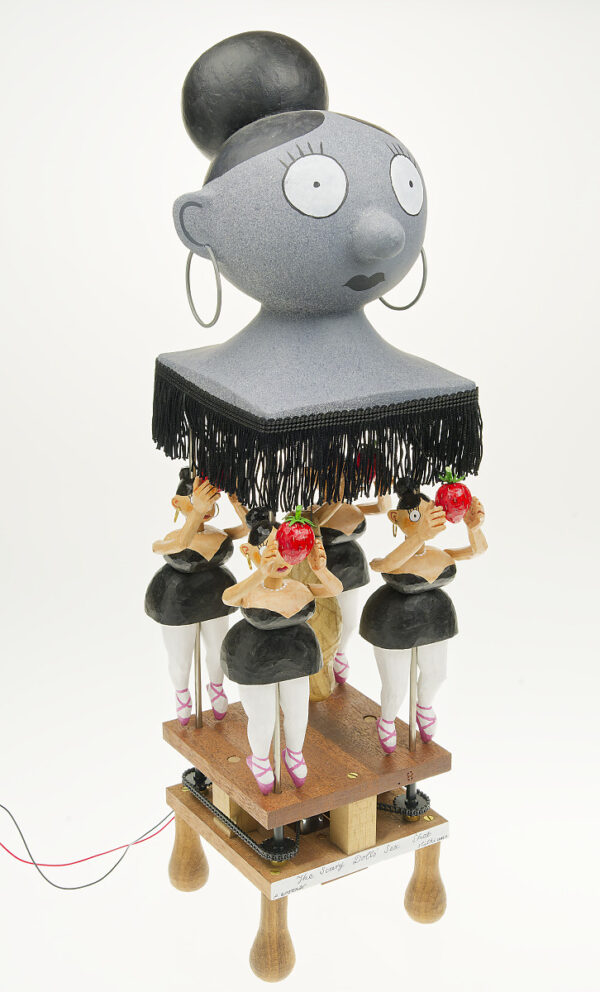 4 hand carved and painted doll figures in black dress, white tights, pink ballet shoes. They stare straight ahead holding giant strawberries in fornt of their faces. A grey doll head floats above them.